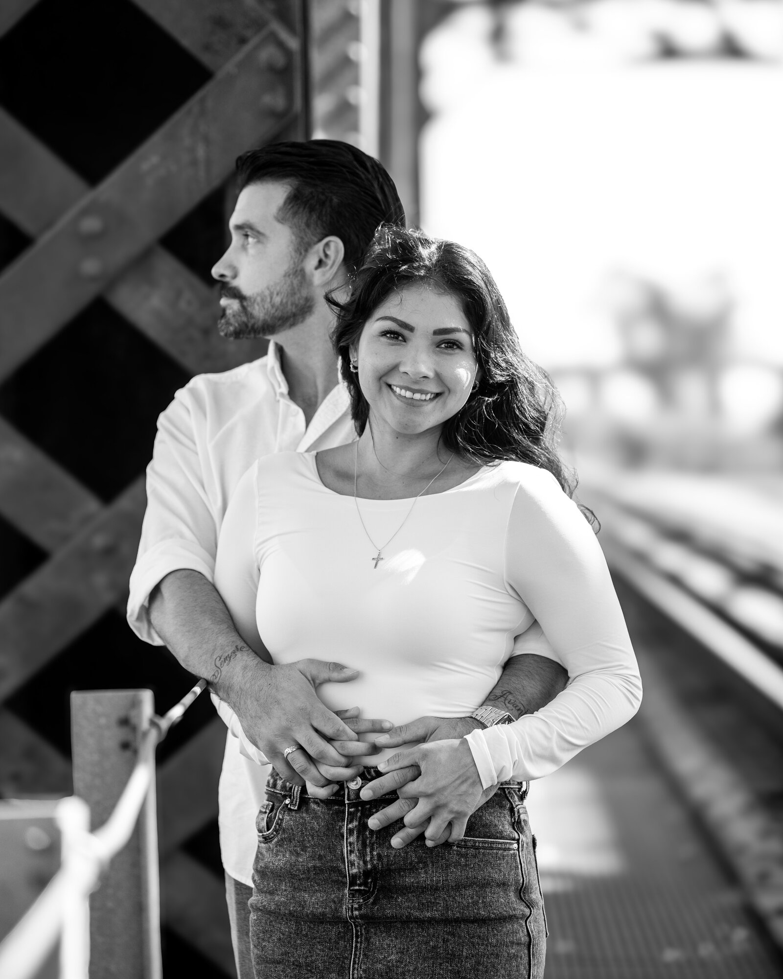 Black and white portrait of an engaged couple at a railroad trestle