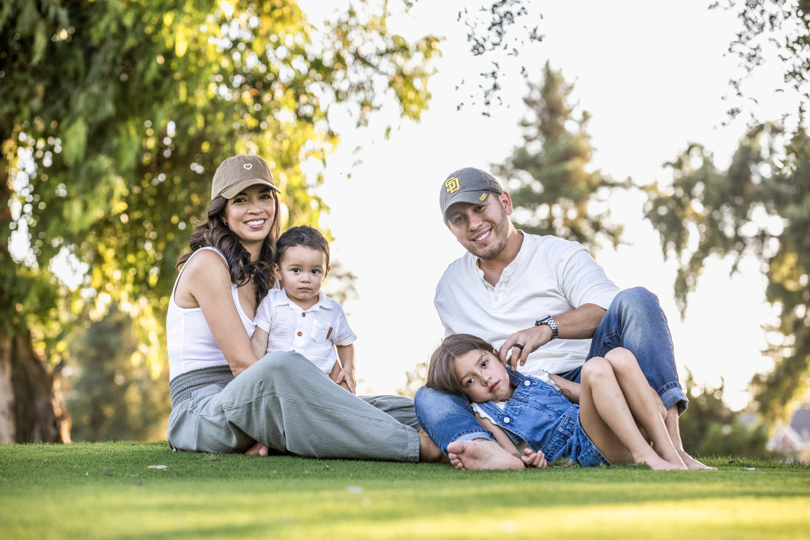 Family of four together on the grass in golden evening light