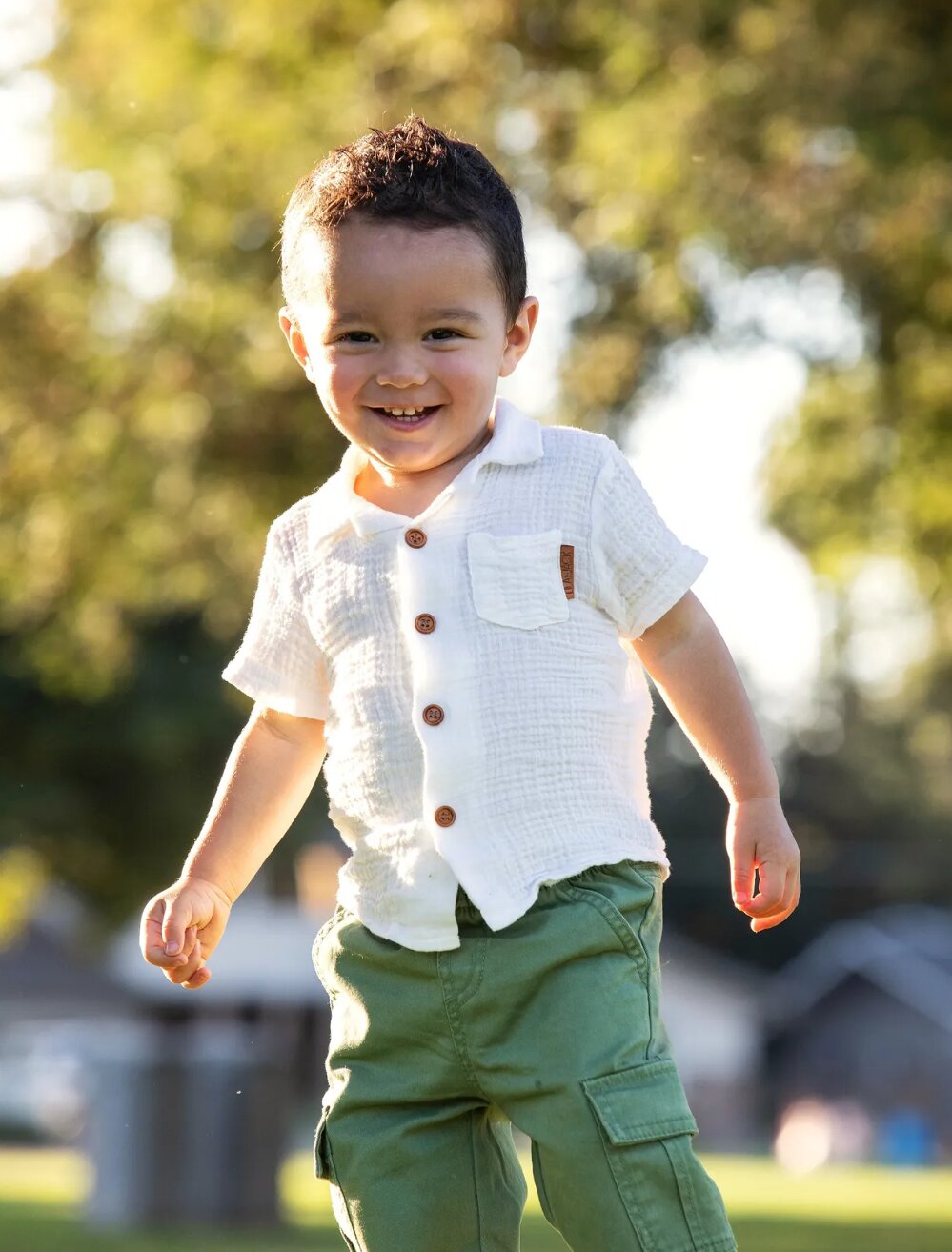 Toddler running and laughing across a sunlit park