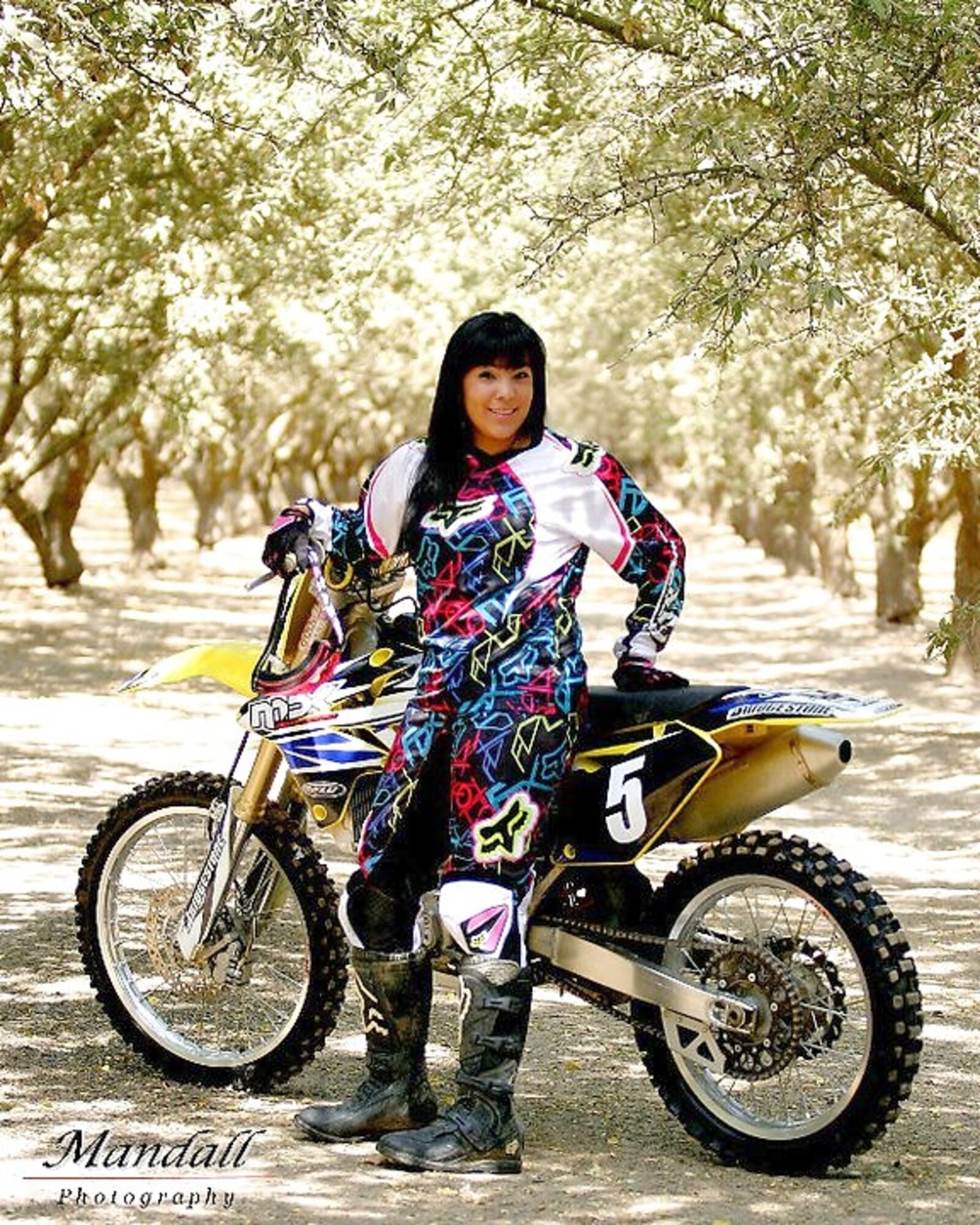 Senior portrait of a motocross rider in a sunlit orchard