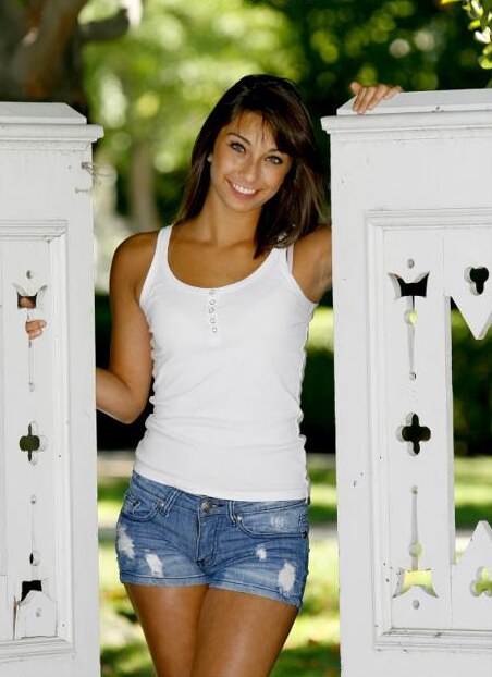 Senior portrait of a girl between two white garden gateposts